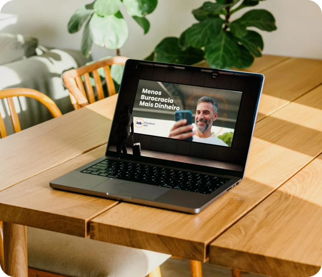 Laptop exibindo "Menos Burocracia Mais Dinheiro" com homem sorrindo